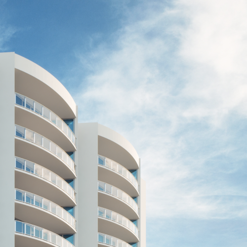 The image shows a modern apartment building with curved balconies against a blue sky with some clouds, ending the sentence.