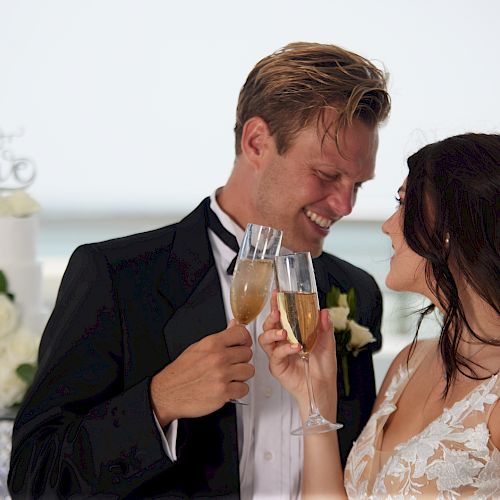 A bride and groom are toasting with champagne. The bride is wearing a white dress, and the groom is in a black suit and bow tie.