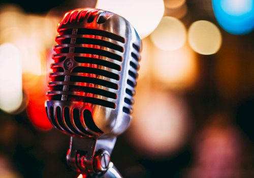 A close-up photo of a vintage-style microphone with colorful bokeh lights in the background, creating a warm and nostalgic atmosphere.