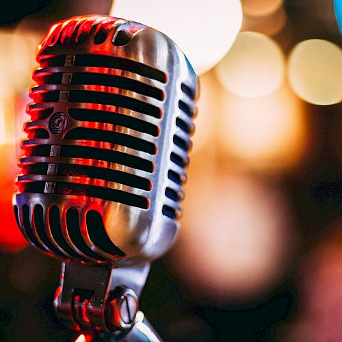 A close-up photo of a vintage-style microphone with colorful bokeh lights in the background, creating a warm and nostalgic atmosphere.