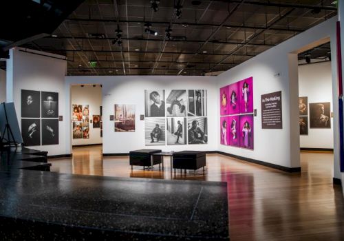 An art gallery room with framed black-and-white and colorful photo displays on the walls and benches in the foreground.