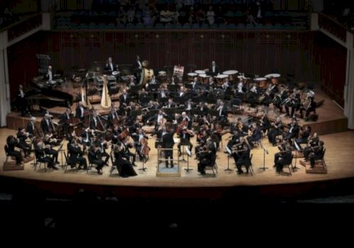An orchestra performing on stage, complete with various instruments and musicians in formal attire.