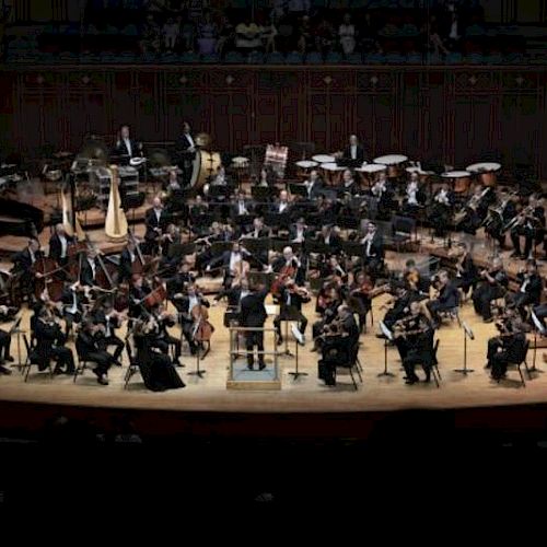 An orchestra performing on stage, complete with various instruments and musicians in formal attire.