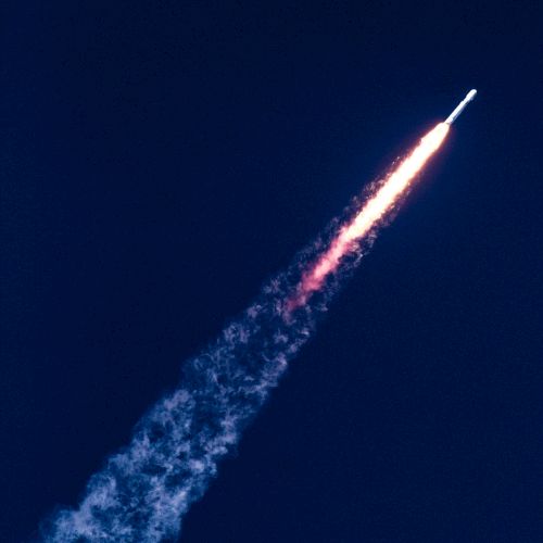 The image shows a rocket launching into the sky, leaving a trail of exhaust and smoke behind it against a dark background.