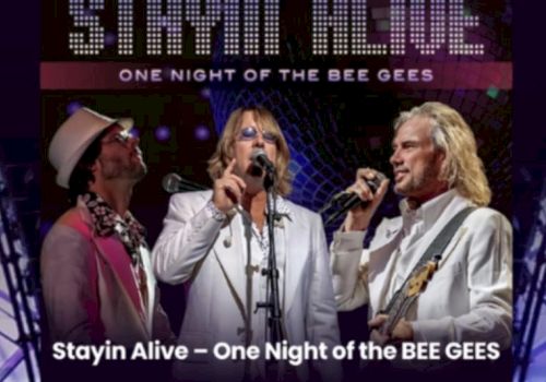 A concert poster showing three men in white singing with guitars and microphones, titled &ldquo;Stayin Alive &ndash; One Night of the BEE GEES.&rdquo;.