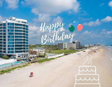 The image features a beach with buildings on one side, 