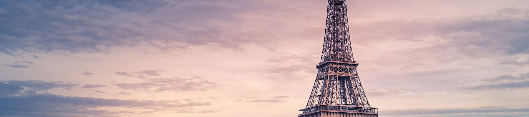 The image contains the Eiffel Tower in Paris, France, with the Seine River in the foreground and a beautiful sunset in the background.