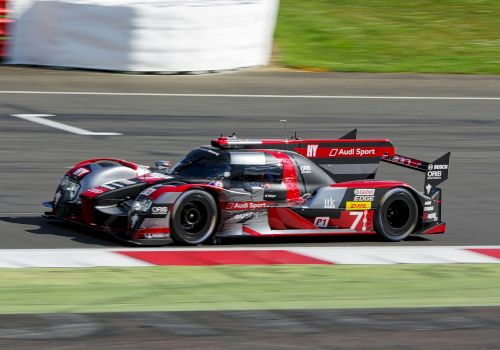 A high-performance Audi racing car on a track, showcasing speed and aerodynamic design, with visible branding and sponsorship.