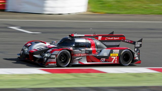 A high-performance Audi racing car on a track, showcasing speed and aerodynamic design, with visible branding and sponsorship.