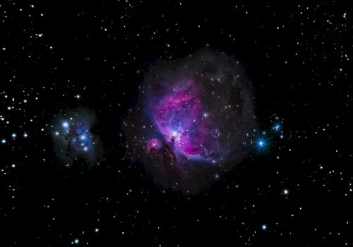 The image shows a colorful nebula surrounded by numerous stars in space, featuring bright purple and blue hues against a dark background.