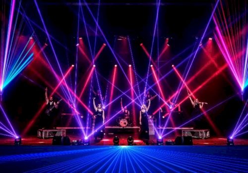 A vibrant stage performance with musicians, drummers, and colorful laser lights creating dynamic patterns in a lively atmosphere.