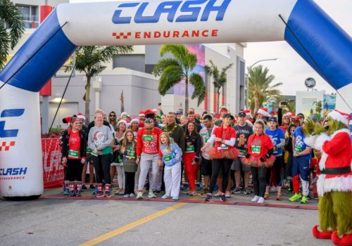 A group of runners and Santa-clad people pose at a &ldquo;CLASH Endurance&rdquo; inflatable arch before a race.