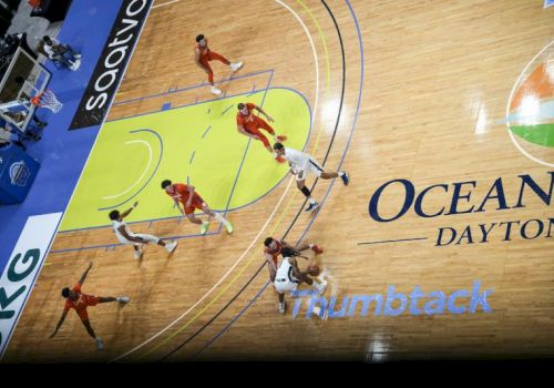 A basketball game viewed from above, with players in action on the court featuring logos and markings.