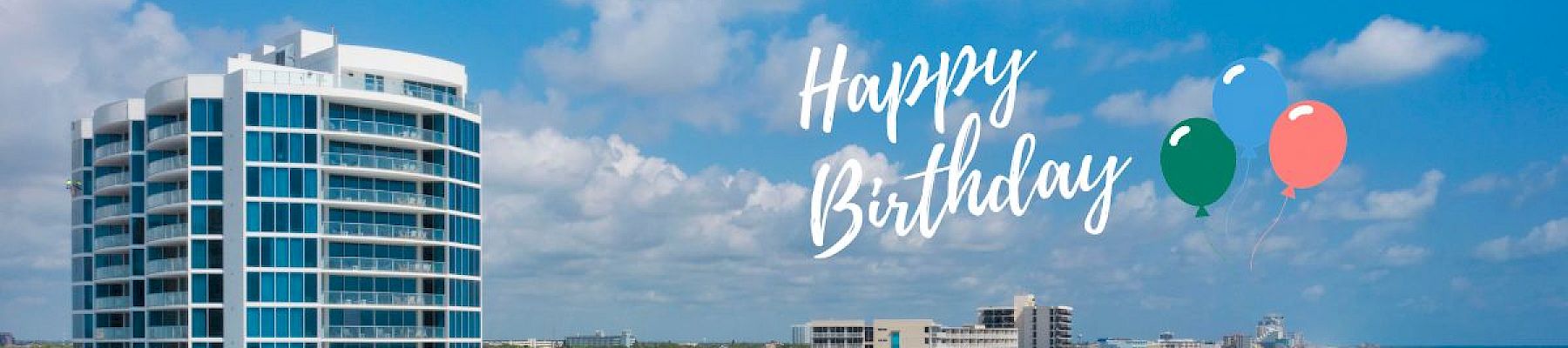 A beachfront scene with buildings, a sandy shore, and ocean waves. "Happy Birthday" text, balloons, and cake graphic with number 3.