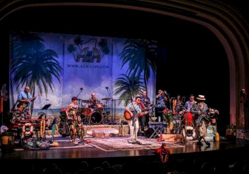 A band performs on stage with tropical decor, palm trees, and various instruments, creating a lively atmosphere.