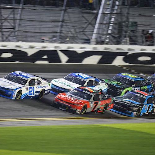 This image shows a group of race cars on a track, with "Daytona" visible in the background.