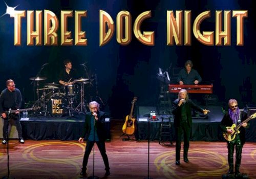 A band performing on stage with "THREE DOG NIGHT" written above them in large letters.