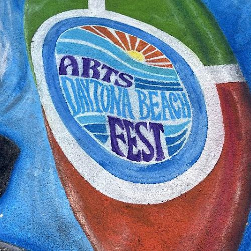 A colorful street art piece features "Arts Daytona Beach Fest" with a sun and wave design in vibrant hues.