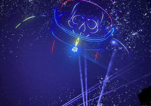 The image shows a neon-style drawing of an astronaut with a skull face, surrounded by stars and beams of light on a dark background.