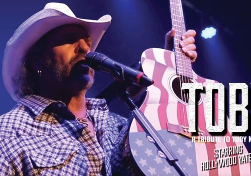 A country singer in a cowboy hat sings into a mic while playing an electric guitar on a patriotic backdrop, with &ldquo;TOB Y&rdquo; text.